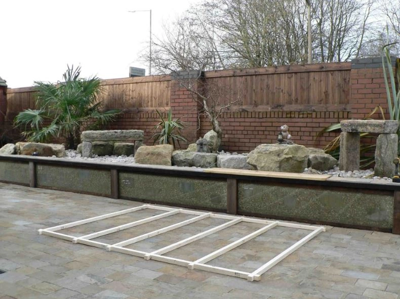 a shed base positioned in a garden and amongst a rock display.