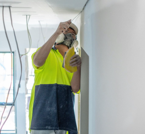 an image of a man with hi-vis preparing a wall for plasterboard