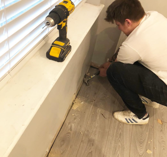 an image of a man using hammer to take skirting boards out