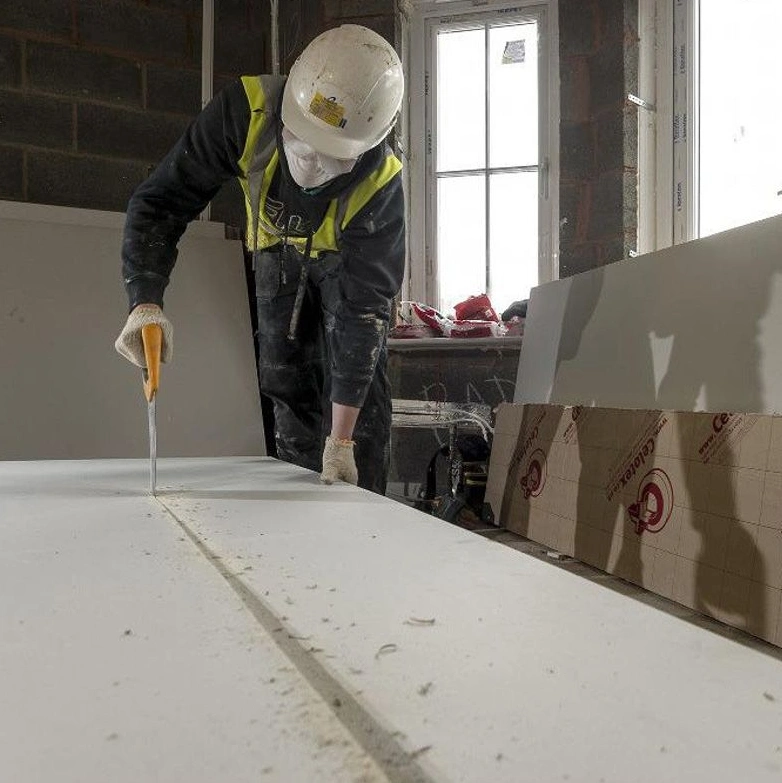 A man cutting into plasterboard using a saw to initiate precise cuts.