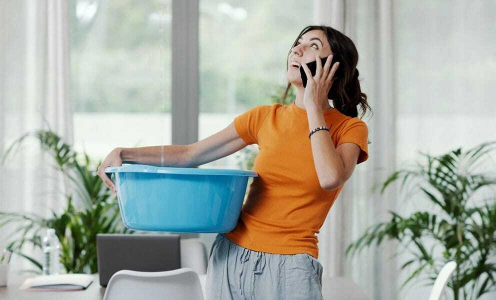 A woman on the phone holding a bucket looking up at the ceiling