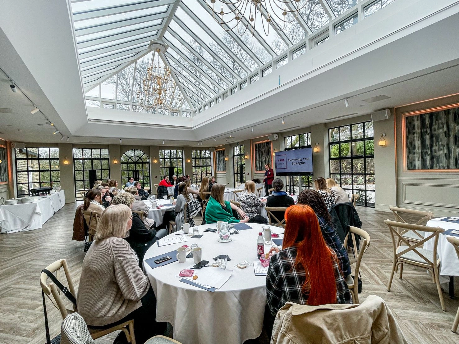 A room full of tables and chairs with women attending the women's day network event ran by Howarth, an event to celebrate and empower the women within the business.
