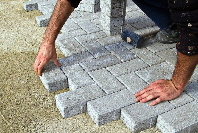 an image of a man aligning block paving against one another