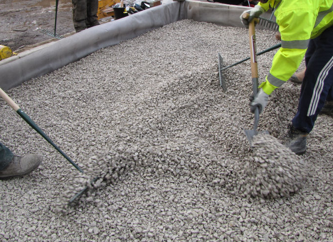 an image of men applying rock subbase for block paving