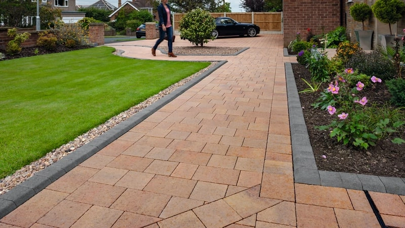 An image of Marshall's standard concrete block paving being used as a driveway. Behind the driveway is also a detached house and a white garage. 
