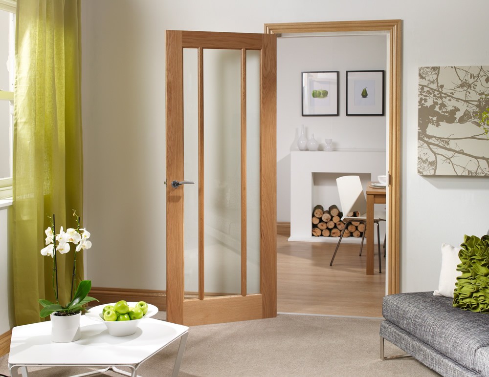 An image showing a Worcester 3 Panel Internal Oak Fire Door in aliving room leading open to the dining room. White walls, green curtains on the left and beige carpet. 