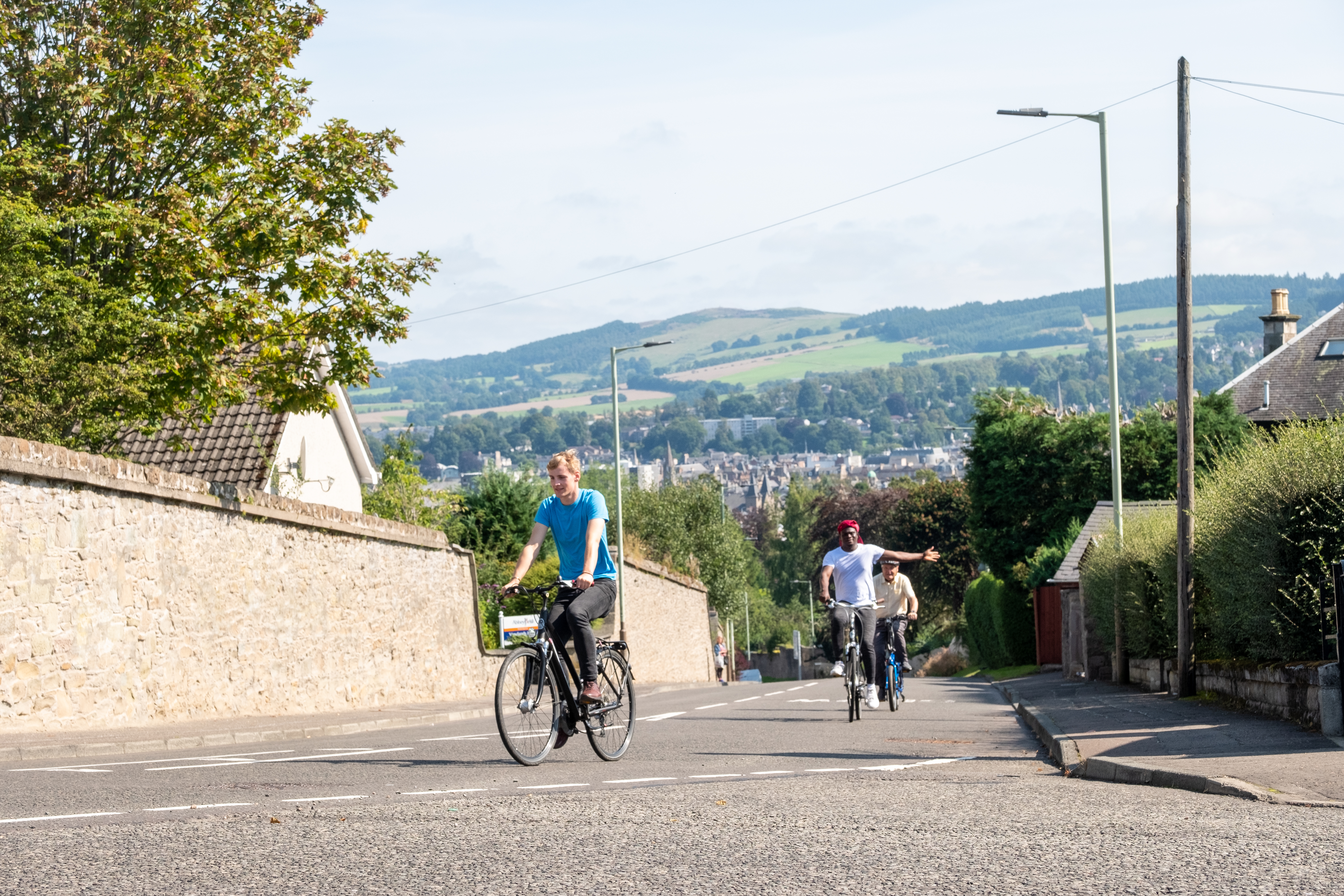 a group of three men riding bikes on the road