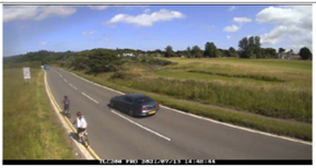 a car passes a person on a bike with plenty of space on the road