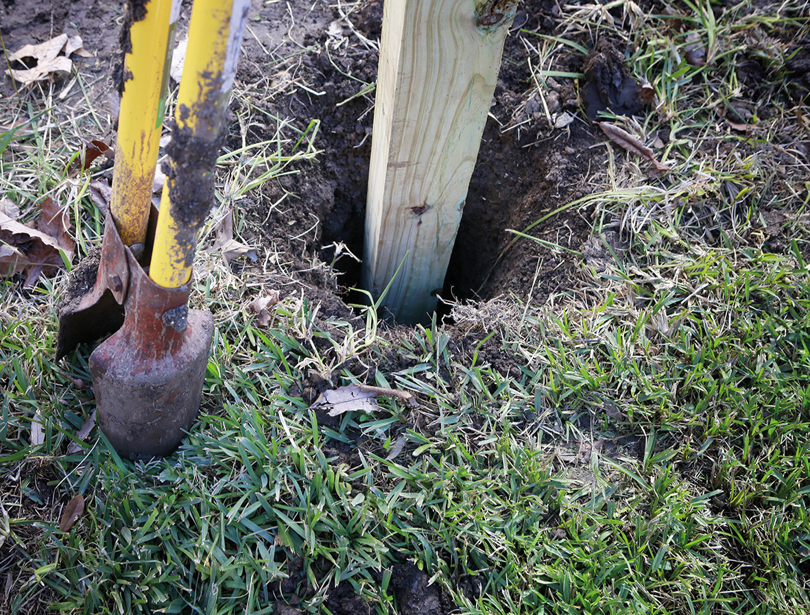 A wooden timber post being fitted in a hole in the ground. 