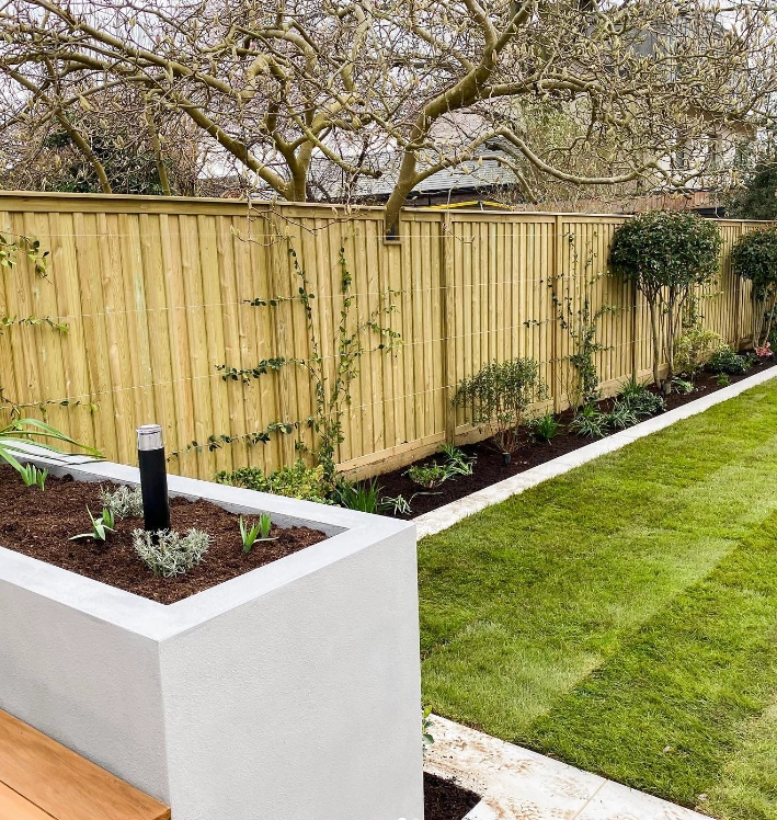 an image of a beige coloured fence used amongst a garden with green grass.
