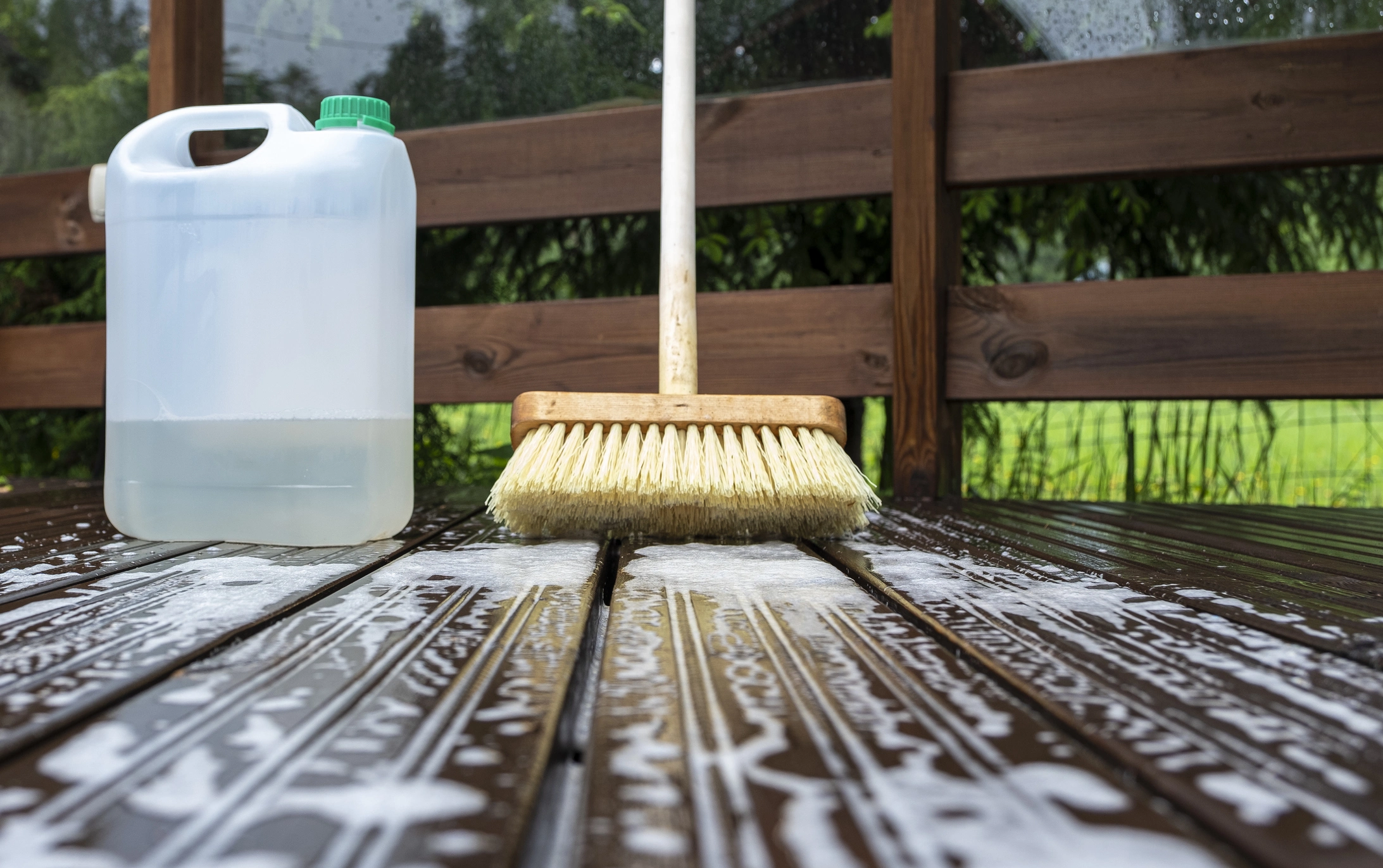 Picture and water and soap being used to clean over and maintain a wooden timber deck. 