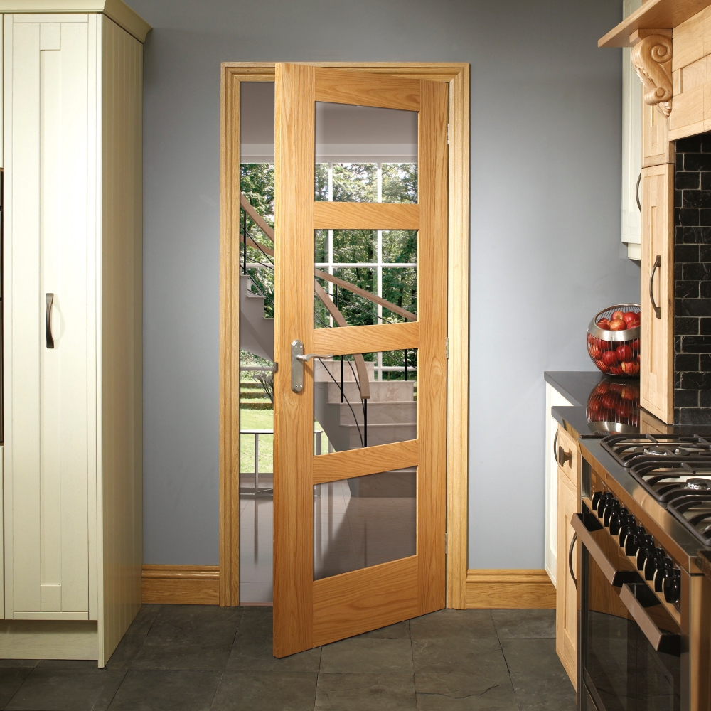An image showing a Shaker 4 Light Pre-Finished Internal Oak Door with Clear Glass leading from the kitchen.  Oven  on the right hand side and units on the left hand side.