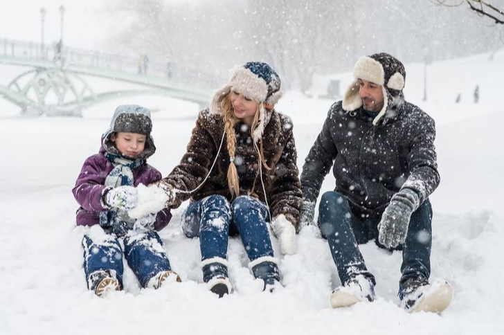 an image of a family outside playing in the snow. Man, woman and child