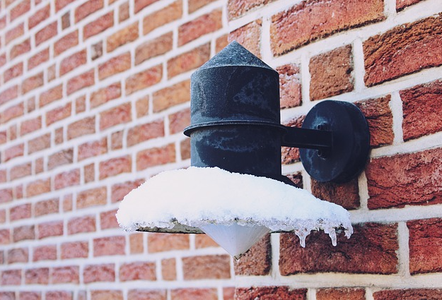 an image of an icy outdoor light against a red-bricked home
