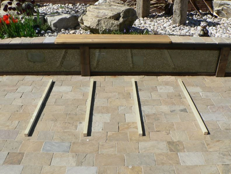 Shed base placed on a tiled garden in front of a rock display.