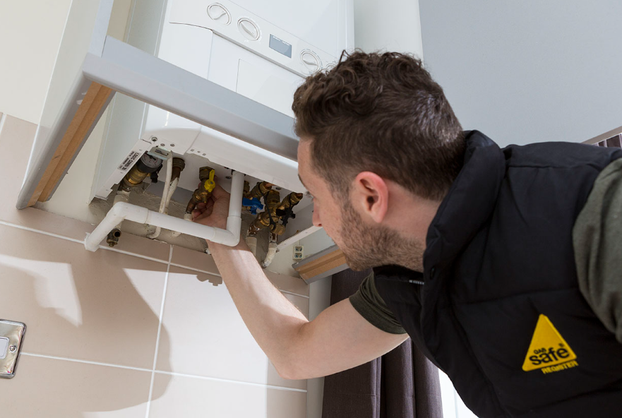 an image of a man fixing and checking a boiler within the home