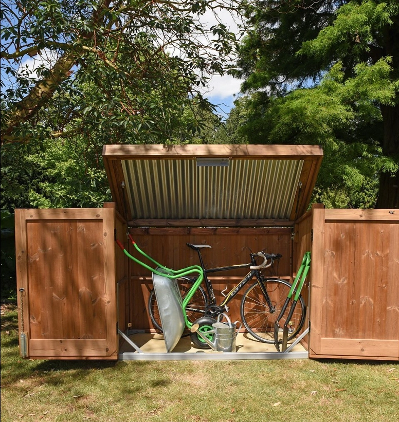 A wooden garden storage box with a roof, holding a bright green bike within it.