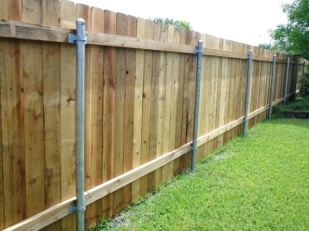 an image of a wooden timber fence with circular, concrete posts amongst green grass.