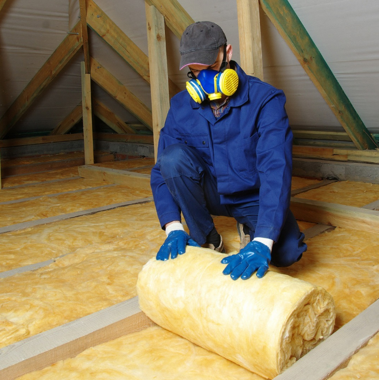 man fitting blanket insulation in loft