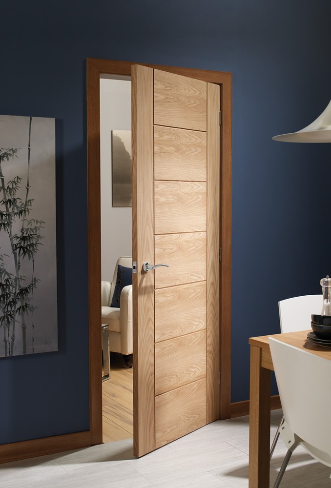 An image showing the Internal Oak Palermo Grooved Flush Door slightly open in a living room. Dark blue painted walls .