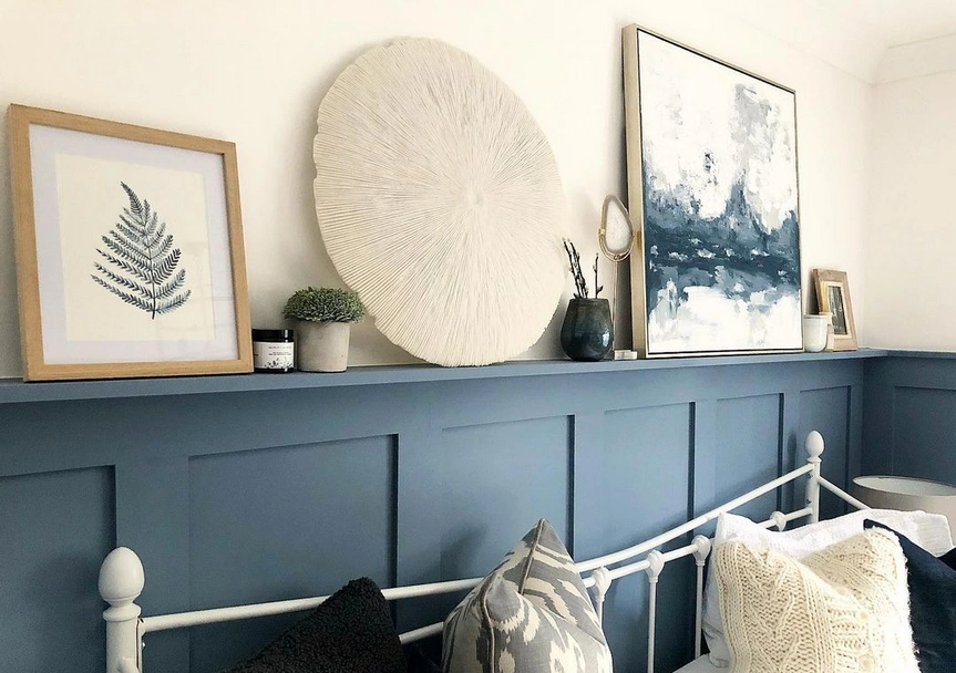 Bright blue wall panelling being used as a shelf to showcase several pieces of painting and art-work.