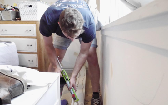an image of a man applying adhesive to skirting board