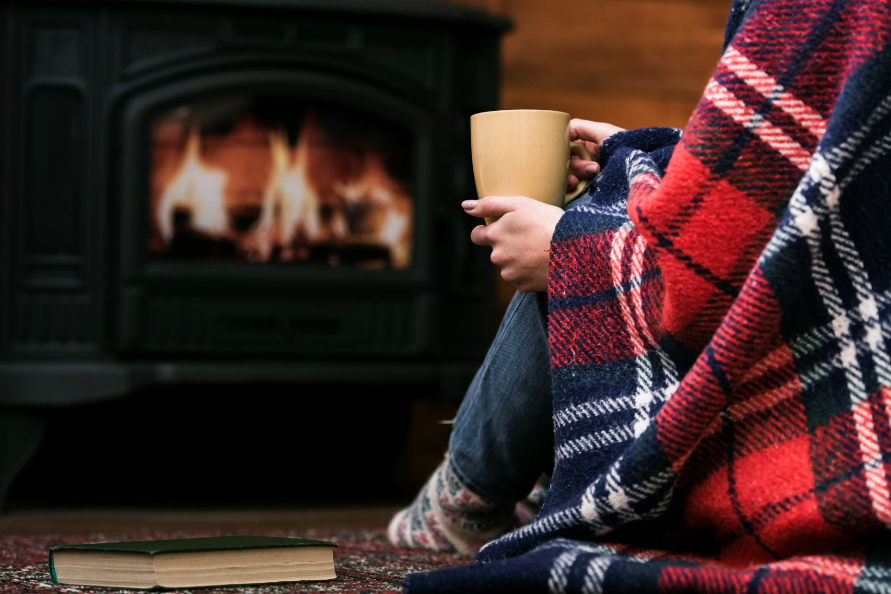 an image of a person holding a cup of coffee by the fireplace