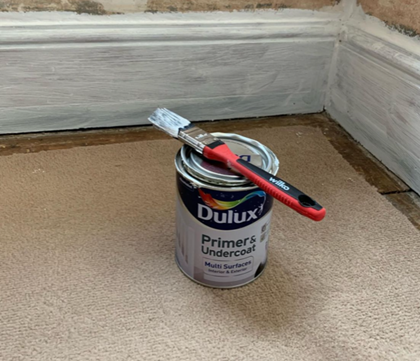an image of dulux paint and paint brush next to painted skirting boards