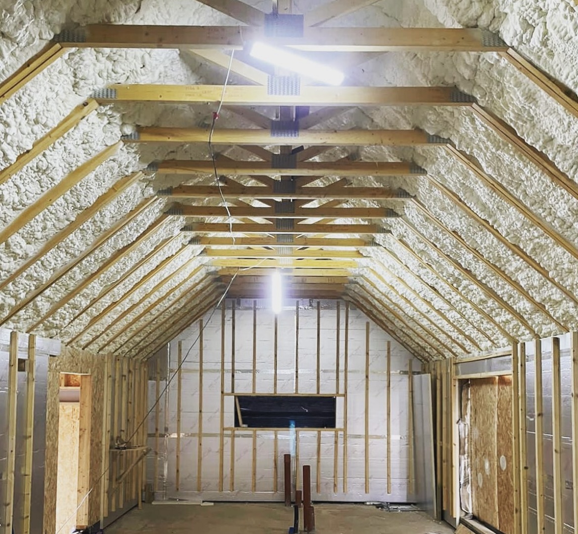 An image showing a room with wooden beams and insulation installed in the roof. Wooden stud walls on each side of the room.