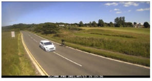 a car passes a person on a bike with satisfactory space on the road