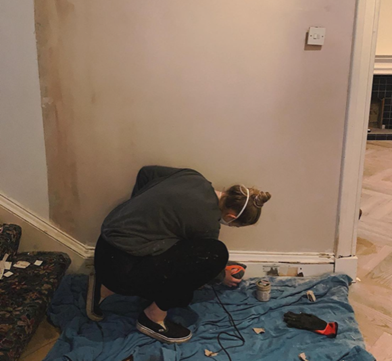 an image of a woman painting skirting board in home