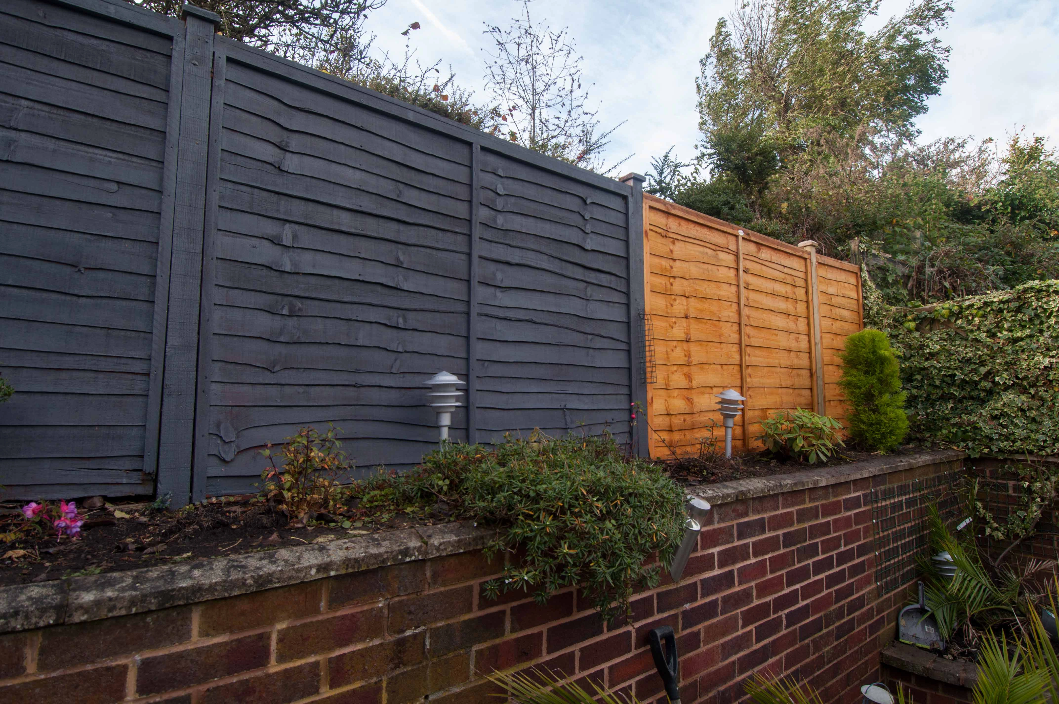 an image of a black and brown colour block fence amongst a red bricked wall.