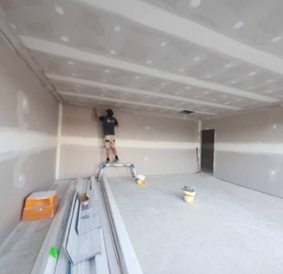 an image of a man painting plasterboard wall