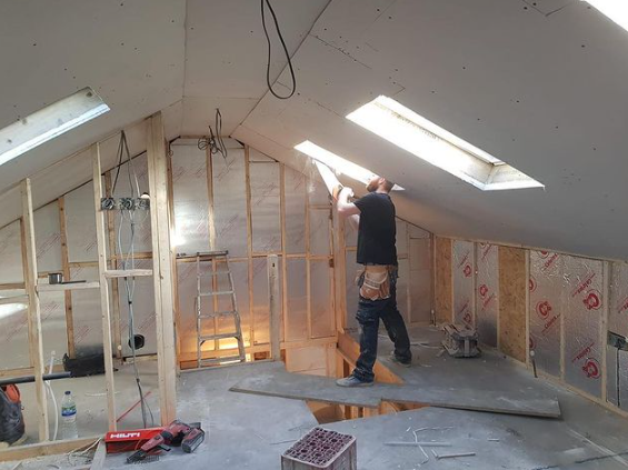 an image of a man fitting plasterboard on ceiling
