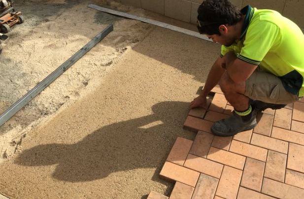 an image of a man in hi-vis applying block paving on top of subbase