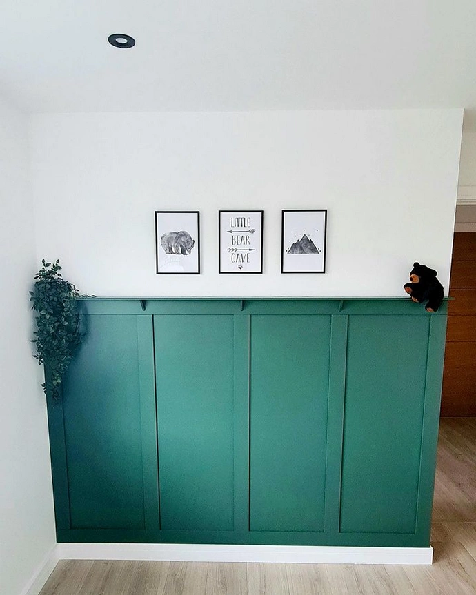 Bright green panelling applied beneath a white statement wall to act as a focal point for within the home. Accessorised with paintings above it.