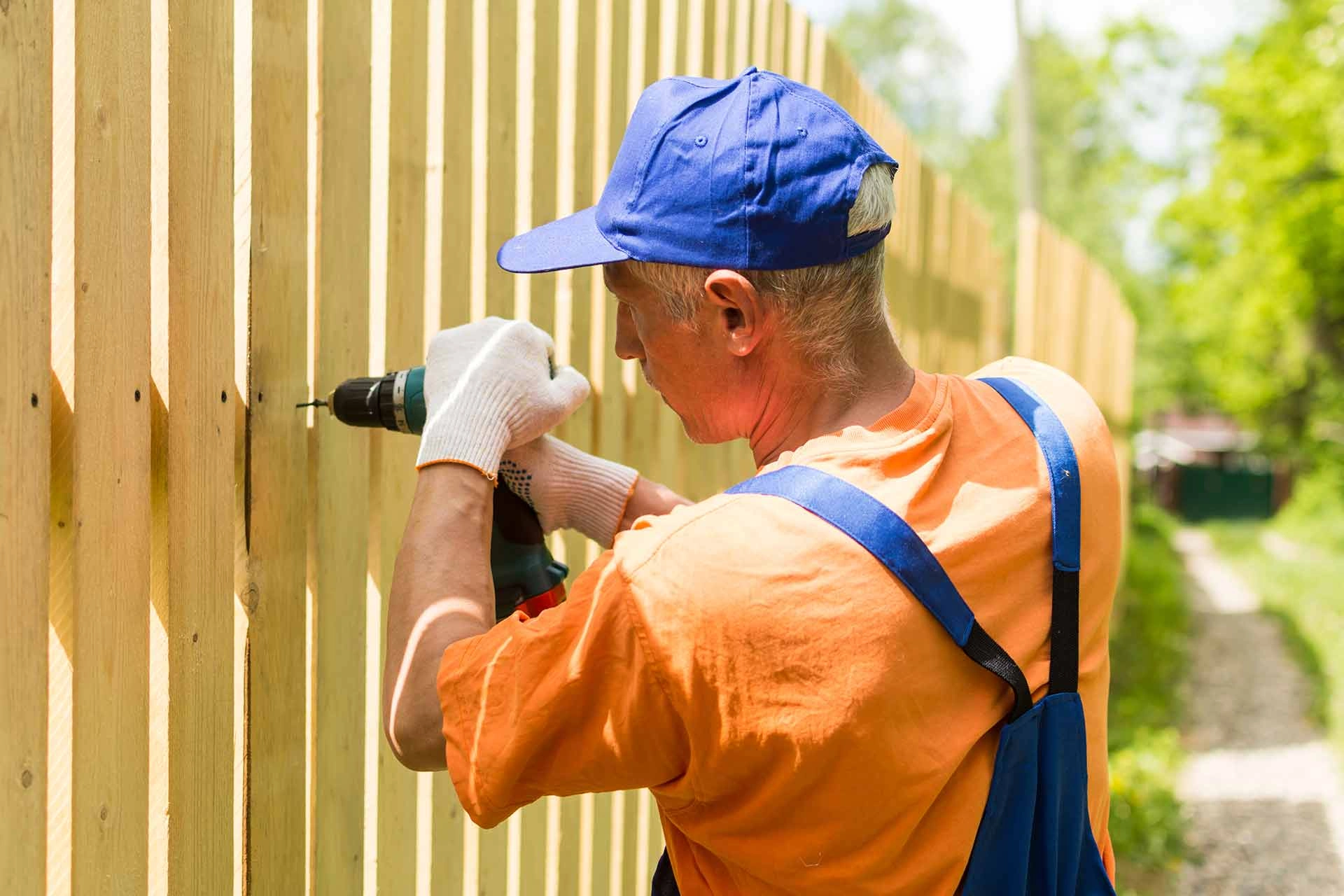 an image of a person using a drill to drill nails into a wooden fence