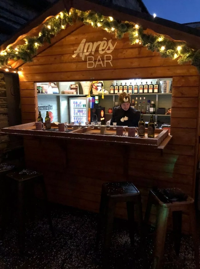 An Apres-Ski type bar with lighting around the top of the bar, and other bar bottles cascaded across the front.