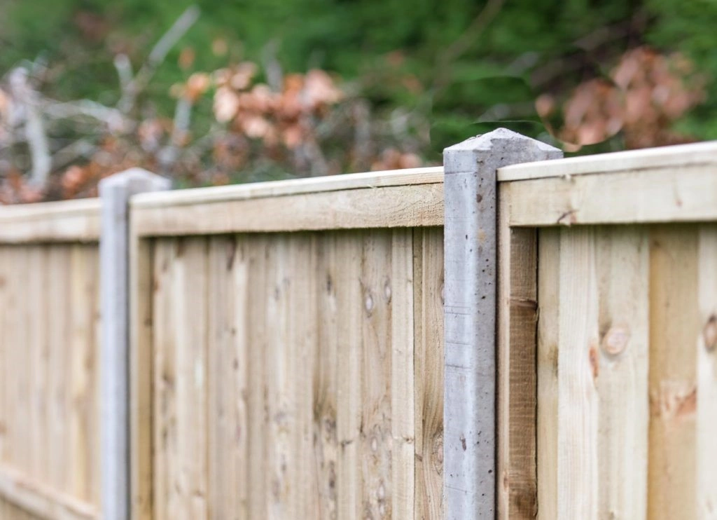 a longshot image of a light-coloured fence with concrete posts