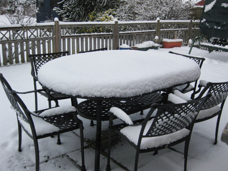 an image of some black metal garden furniture covered in snow