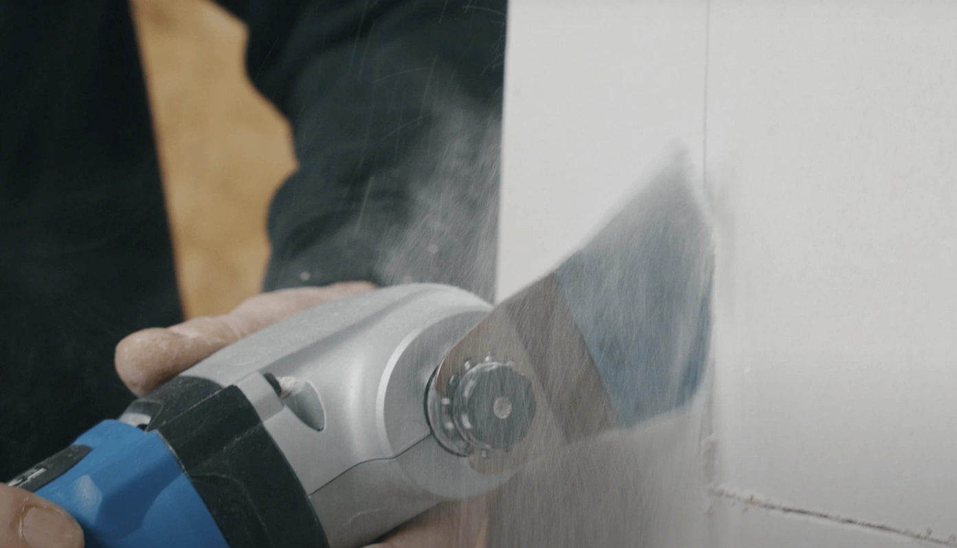 A tool being used to make a deep access hole in plasterboard.