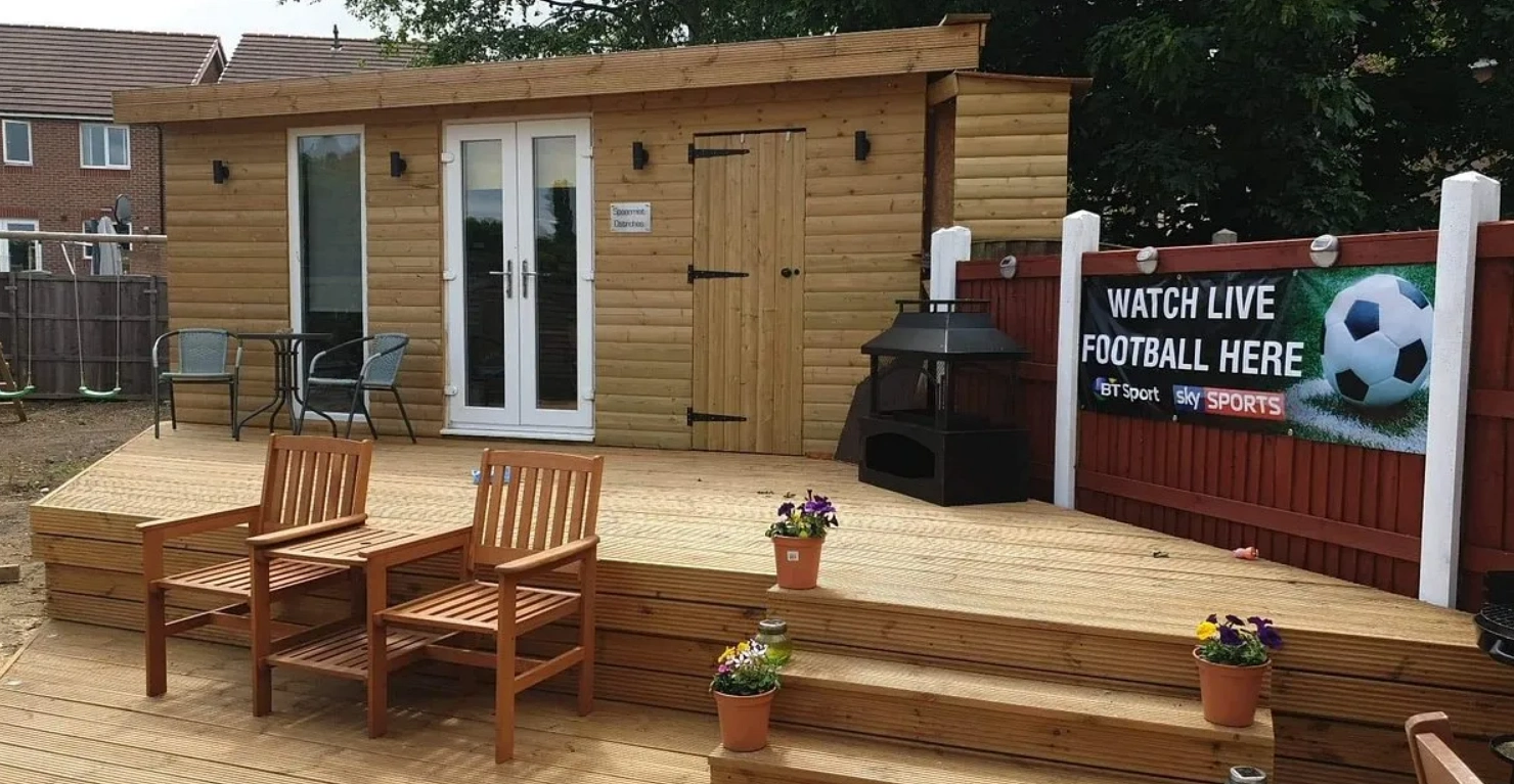 A sports bar situated in the garden with a log burner, a live football banner and outdoor seating.