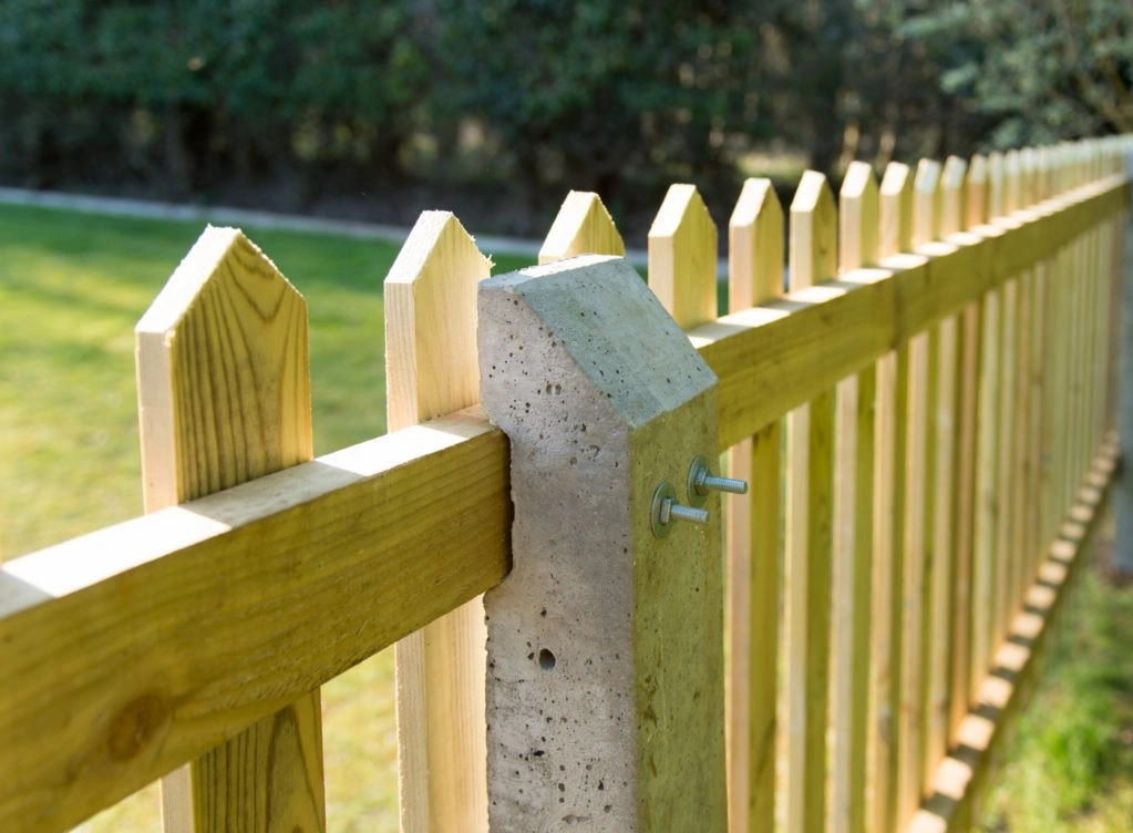 an image of a longshot angle of a wooden picket fence, with nails inserted into the posts.