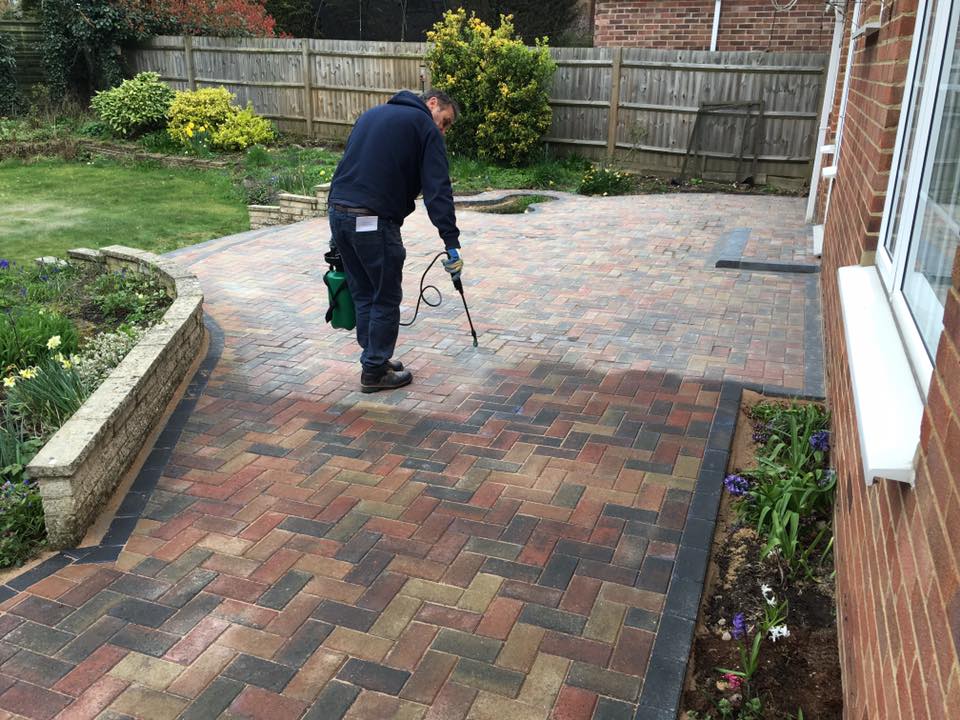 an image of a man jet washing the block paving to clean it