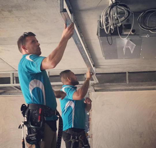 an image of men in blue tops cutting plasterboards