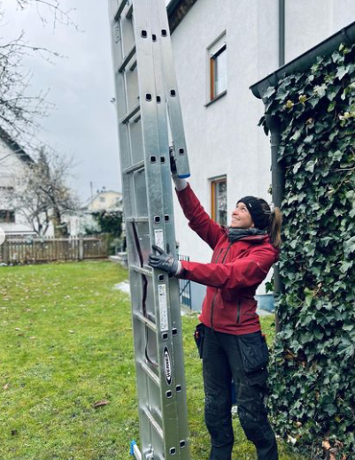 an image of a woman holding chrome ladder outside modern home