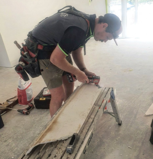 an image of a man cutting plasterboard in white room